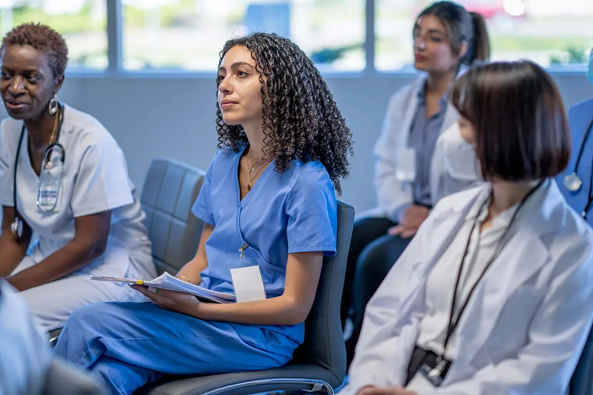 A group of nurses and nursing students in a meeting.