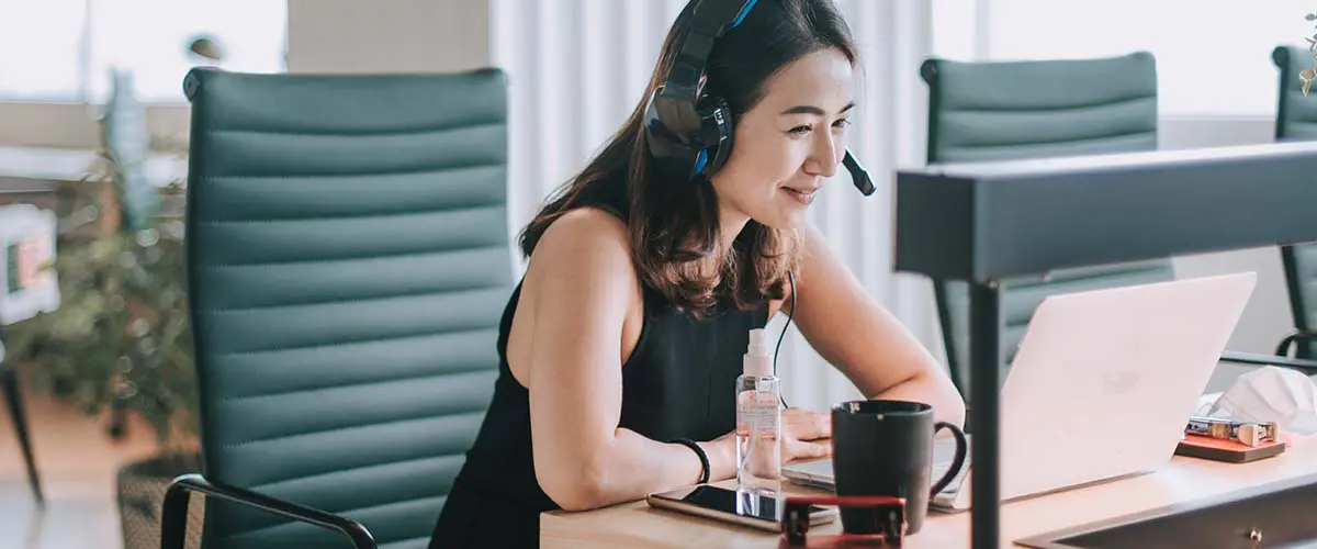 A woman wearing headphones watching a training on her computer.