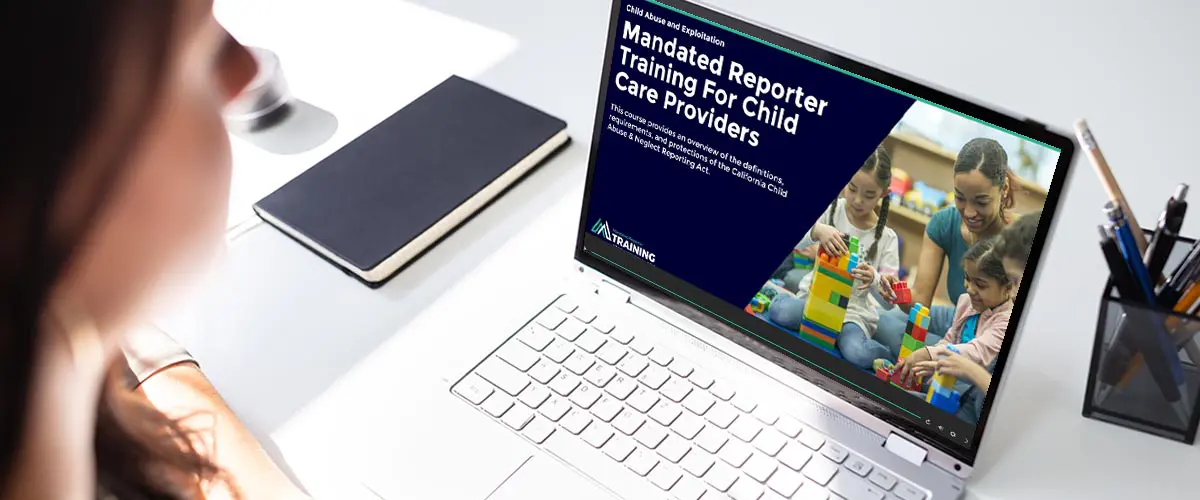 Image of a woman sitting at a desk taking a Mandated Reporter Training course on her laptop.