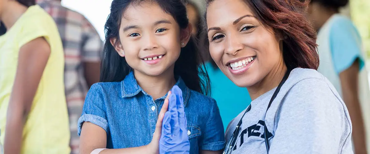 Image of a medical professional volunteering their time and giving a little girl a high-five.
