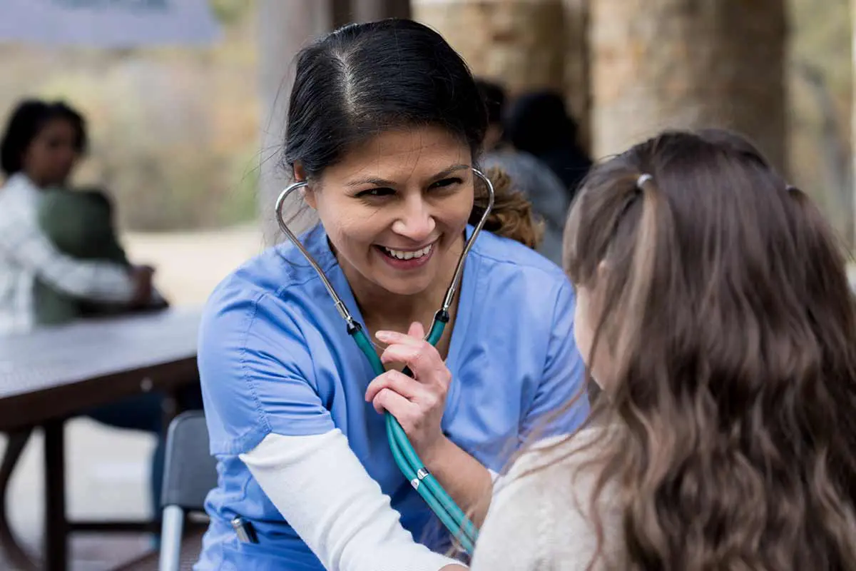 A volunteer nurse works with a child at a free clinic.
